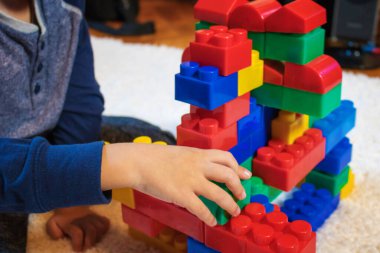 Small boy playing with toy blocks on the carpet. Creative kid building something with plastic blocks.