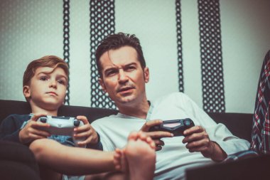 Mid adult father playing video games with his son at home. 