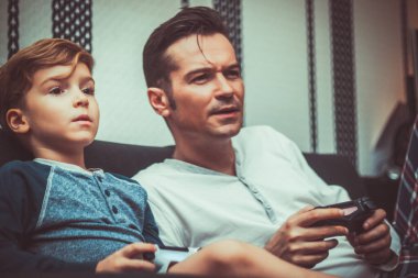 Son and father playing video game and spending a day together. 