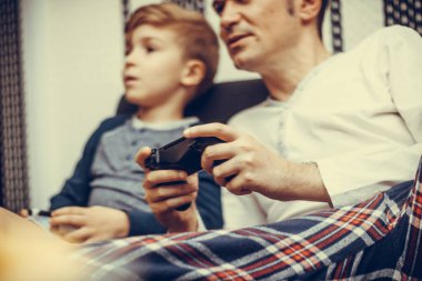 Close-up of father playing video games with his son at home.