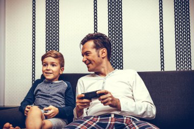 Happy father and son having fun while playing video games at home. 