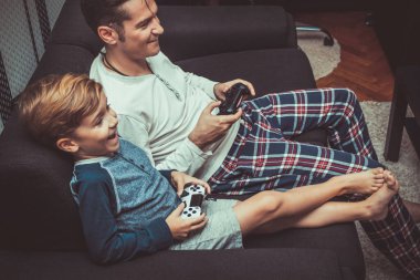 Happy son having fun with his father while playing video game at home. 
