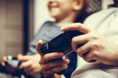 Close-up of parents and child playing video games together. 