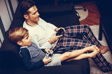 High angle view of small boy playing video games with his father at home. 