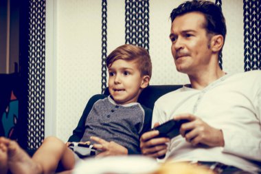 Father and son playing video games and having fun at home. 