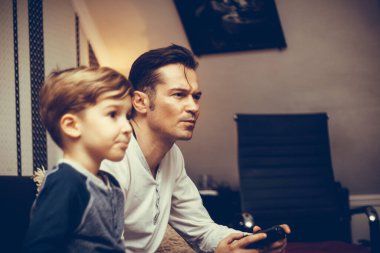 Mid adult man playing video games with is son at home.