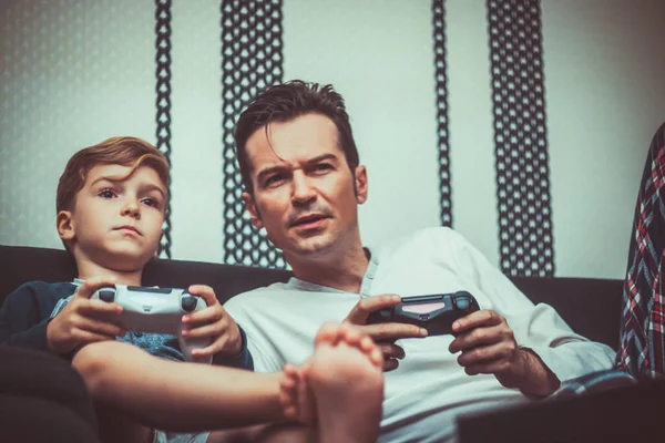 Mid adult father playing video games with his son at home. 