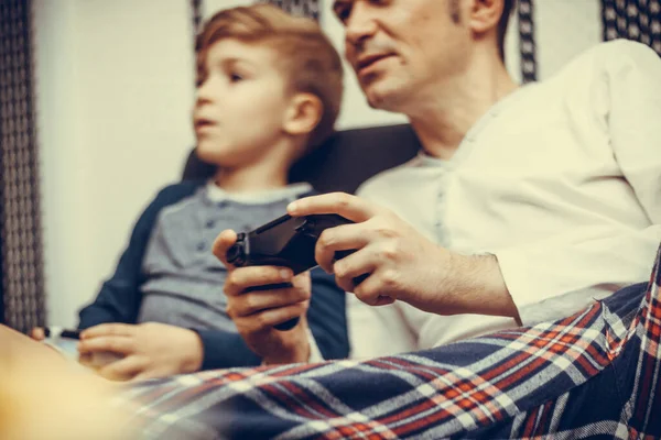 Close-up of father playing video games with his son at home.