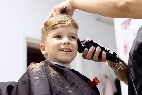 Blond little boy having a haircut at hair salon. 