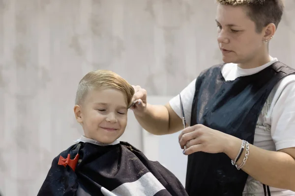 Happy boy getting his hair styled by hairdresser.