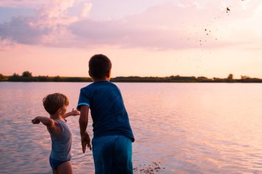 Two boys having fun at beach and playing at sunset on their summer vacation. 