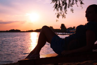 Silhouette of woman enjoying in summer by the sea at sunset.