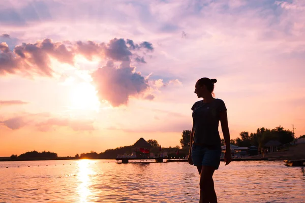 Carefree woman enjoying the view at sunset while being on the beach. 