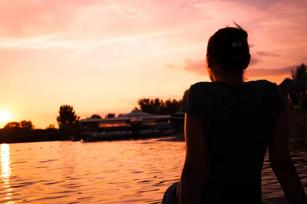 Relaxed woman enjoying the view at sunset by the sea.