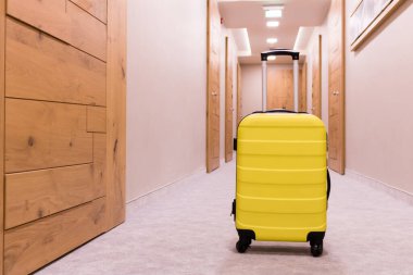 Travel bag in a hallway. Yellow suitcase.