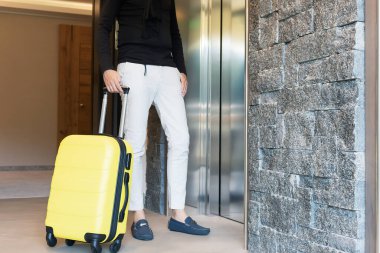 Bavullu tanınmayan bir adam asansörü bekliyor..