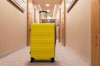 Yellow travel bag with handle in a hallway.