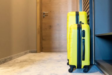 Two yellow travel bags in hotel room.
