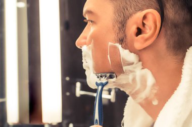 Close-up of man shaving in the bathroom.