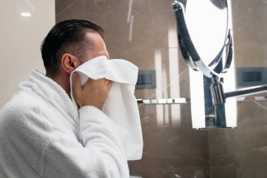 Man using towel after shaving his face in the bathroom.