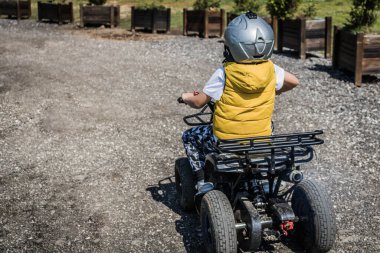 Small boy on off road adventure driving quad bike. 