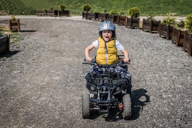 Small boy having fun while driving quad bike.