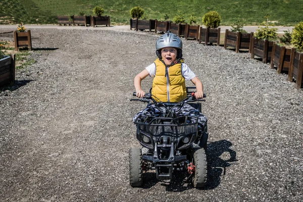 Small boy having fun while driving quad bike.