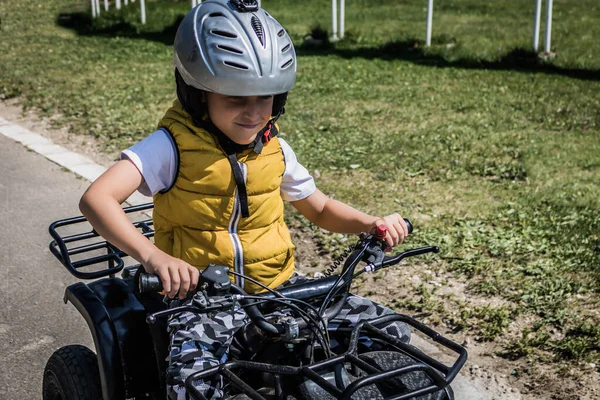 Little boy learning to drive quadricycle on racing track. 
