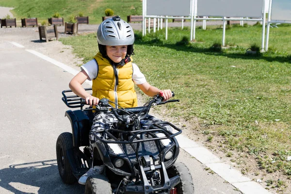 Happy kid having fun while driving 4x4 off road vehicle on the road. 