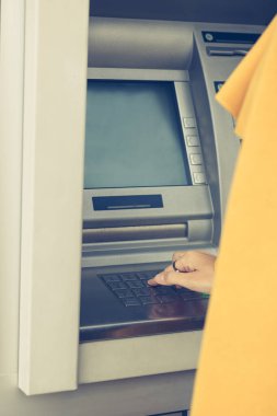 Close up of woman entering pin code on cash machine. Unrecognizable businesswoman typing pin on ATM machine.