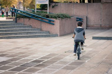Back view of little boy riding a bike while spending a day in the city. 