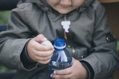 Close up of child opening bottle of water. 