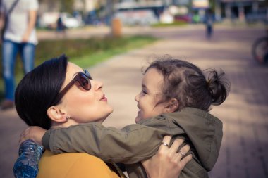 Happy daughter and mother embracing and talking to each other. Happy woman spending time with her little girl.