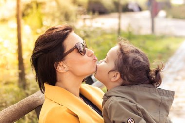 Mother and daughter showing affection towards each other. Little girl is kissing her mother on the chin. 