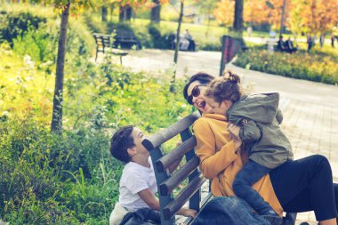 Playful mother having fun with her kids in the park. Joyful family playing outdoors and enjoying in time together.