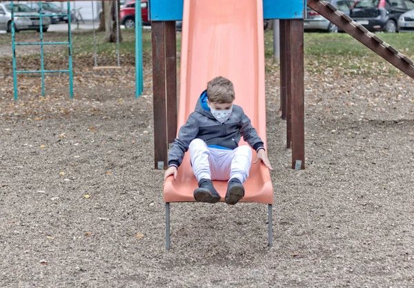 Small Boy Protective Face Mask Sliding Playground — ストック写真