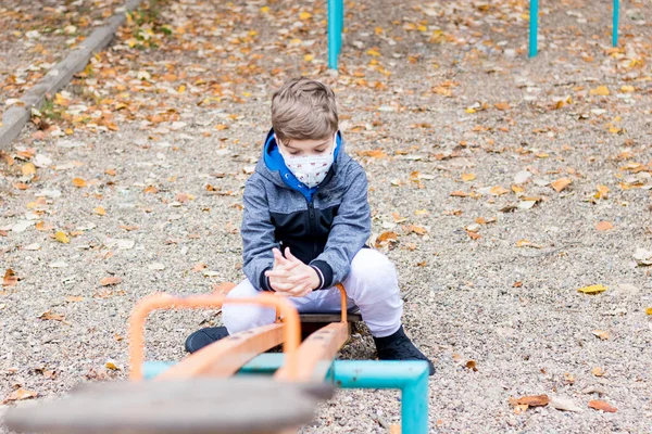 Sad Kid Wearing Face Mask While Sitting Seesaw Empty Playground — ストック写真
