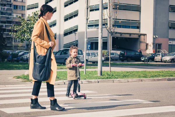 Mother and daughter on zebra crossing. Mother guiding her little girl a cross the street.