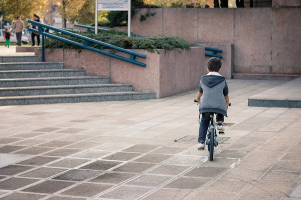 Back view of little boy riding a bike while spending a day in the city. 
