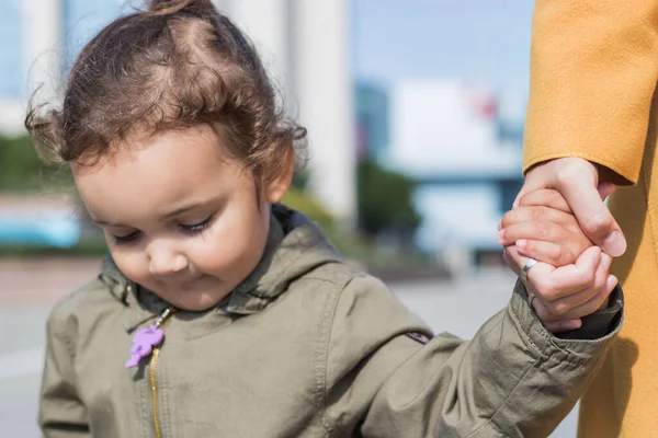Close up of little girl holding hands with her mother. Mother and daughter bonds. 