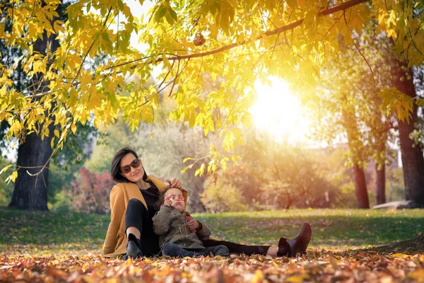 Happy mother enjoying with small daughter in autumn park. Little girl blowing soap bubbles and having fun with her mother in nature.