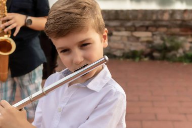Small musician playing flute outdoors.