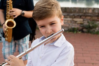 Small boy playing music on a flute. 