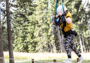 Kid walking on a zip line while being on canopy tour in the forest.