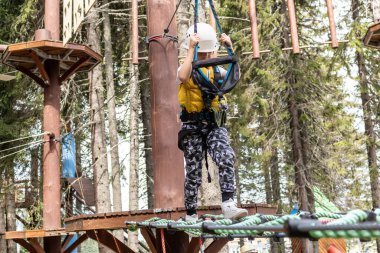 Child walking on a zip line while being on canopy tour in the forest.