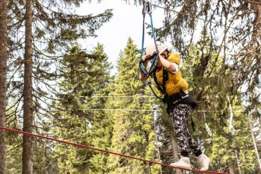 Small kid walking on a rope during canopy tour in nature. 