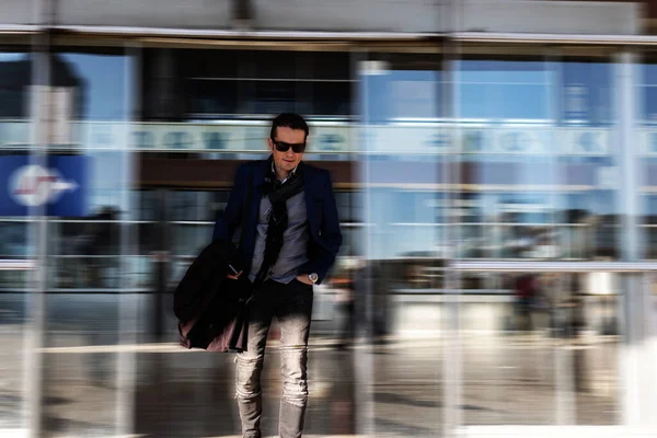Businessman exiting airport terminal in blurred motion.