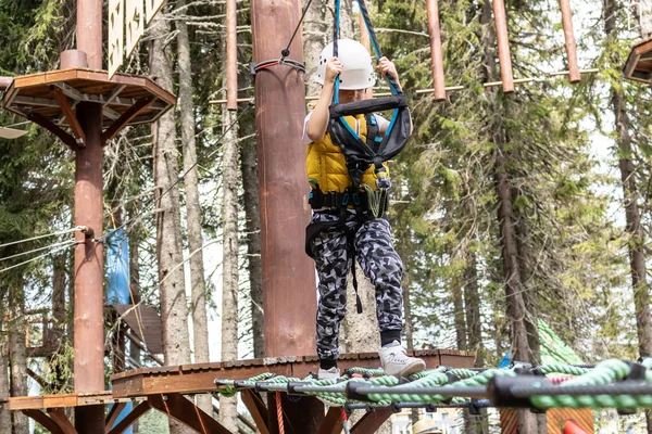 Child walking on a zip line while being on canopy tour in the forest.