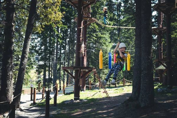 Happy boy having fun while rappelling from zip line in adventure park. 