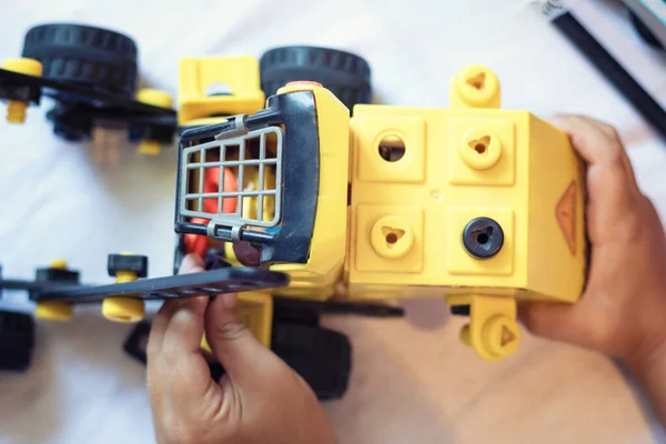 Child playing with toy truck. Close up of kid assembling construction plastic truck.